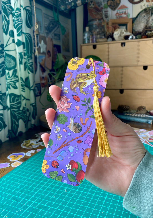 Decorative bookmark with tassel held by a hand in a room setting